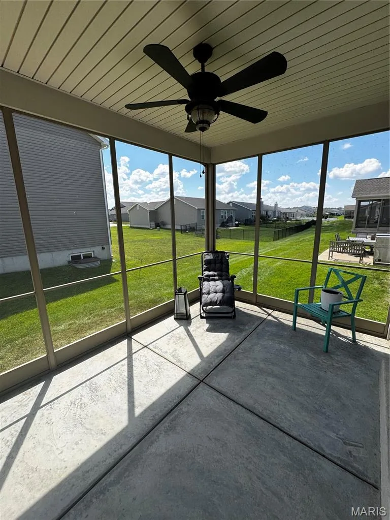Screened outdoor living area with a textured concrete floor, beadboard ceiling, and a ceiling fan with integrated lighting — 401 Copperfield Court, St Charles, MO 63301