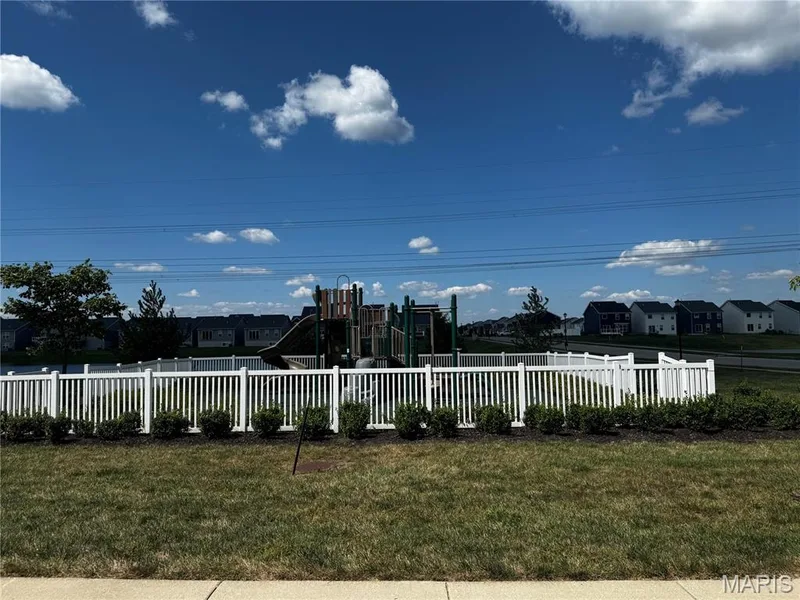 Community playground with a white picket fence, surrounded by manicured landscaping — 401 Copperfield Court, St Charles, MO 63301