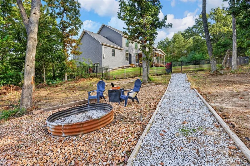 Beyond the fenced backyard, gate entrance to rock path leading to the fire pit in front of pond — 305 Crescent Oak Court, New Melle, MO 63385