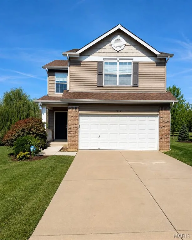Two-story residence featuring a two-car garage, brick accents, and a gabled roofline — 77 Parkgate Court, Lake St. Louis, MO 63367