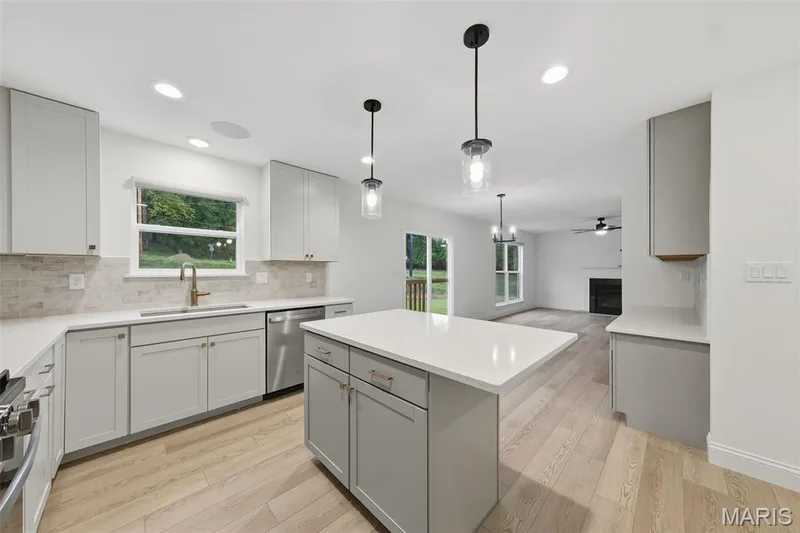 Modern kitchen featuring light-toned cabinetry, stainless steel appliances, a center island with pendant lighting, and wood-finish flooring — 8 Shady Elm Court, St Charles, MO 63301