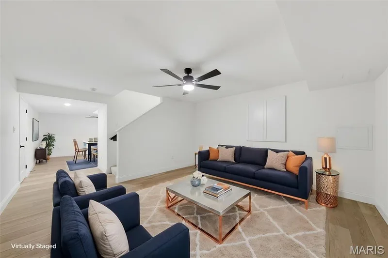 Wood-finish flooring throughout, modern ceiling fan with integrated lighting, open-concept layout, white painted walls, and an interior staircase — 8 Shady Elm Court, St Charles, MO 63301