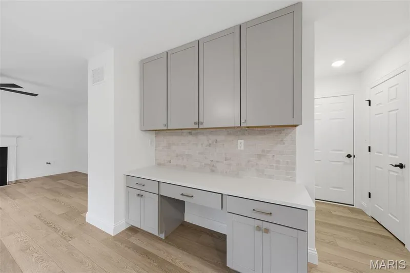 Built-in desk with light gray cabinetry, white countertop, and tiled backsplash — 8 Shady Elm Court, St Charles, MO 63301