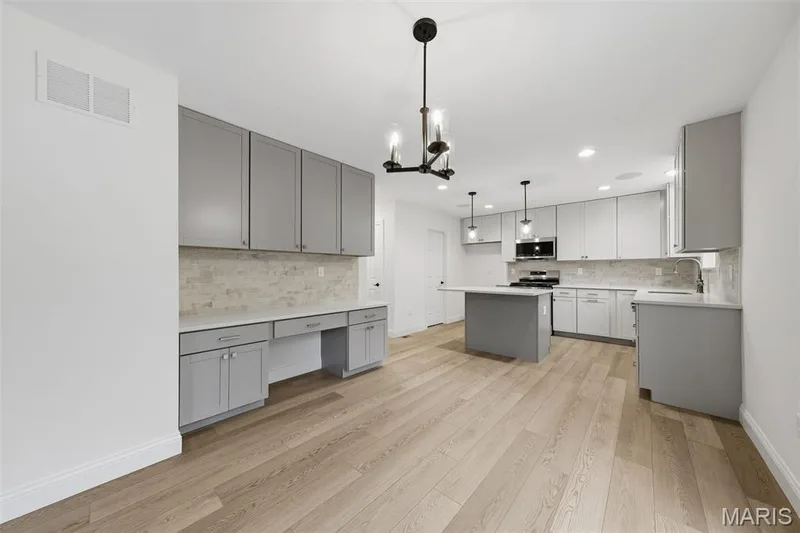 Expansive kitchen featuring light wood-finish flooring, recessed lighting, and a kitchen island with pendant lighting — 8 Shady Elm Court, St Charles, MO 63301
