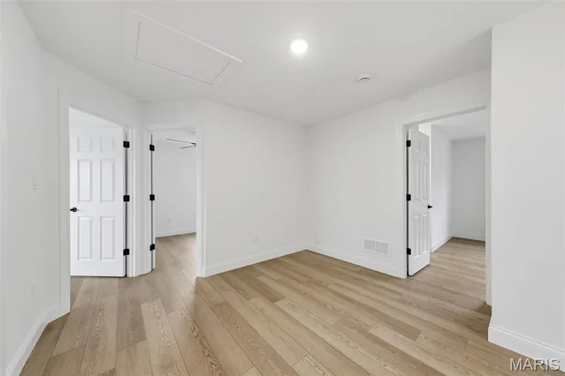 Wood-finish flooring, white paneled doors with matte black hardware, recessed lighting, and crisp white walls — 8 Shady Elm Court, St Charles, MO 63301