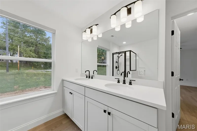 Double vanity with white cabinetry, matte black fixtures, and light-colored countertops — 8 Shady Elm Court, St Charles, MO 63301