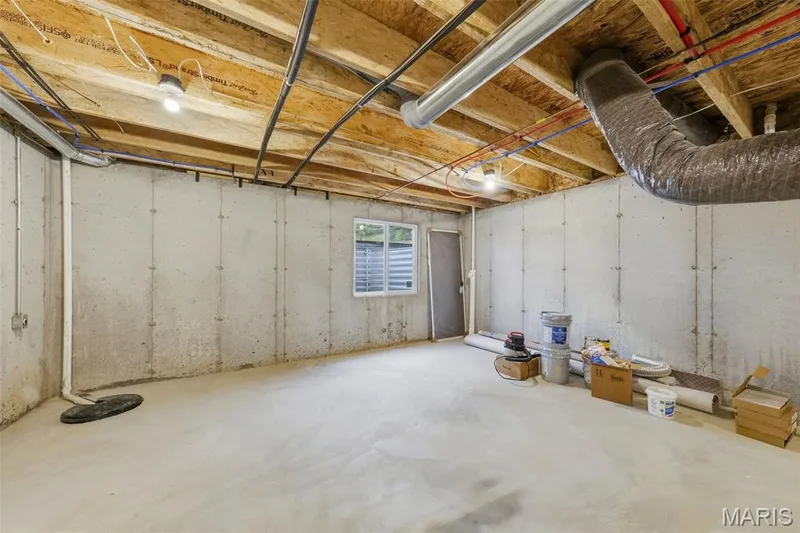Unfinished basement with concrete walls, exposed ceiling joists, and a window with horizontal blinds — 8 Shady Elm Court, St Charles, MO 63301