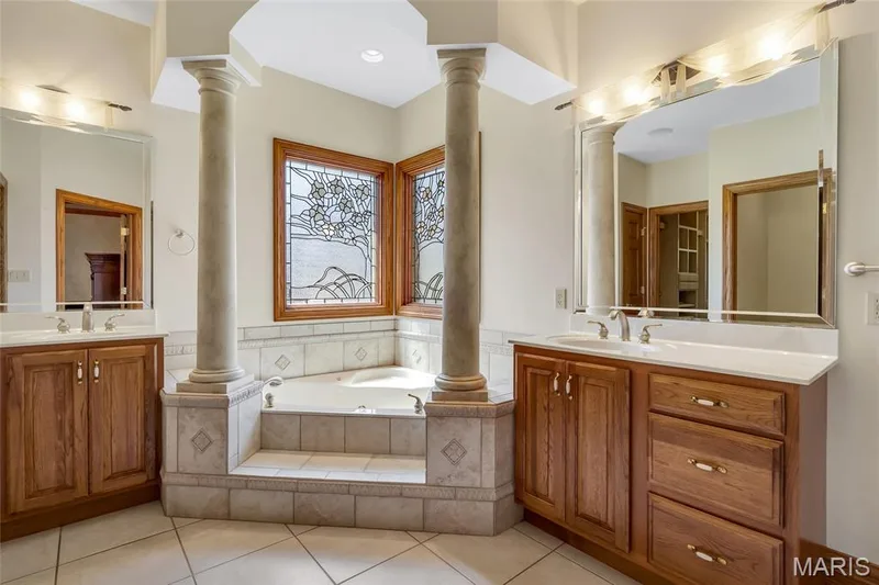 Retreat to the luxurious primary bath, complete with separate vanities and a deep soaking tub designed for relaxation and everyday indulgence. — 4030 Austin Drive, St Charles, MO 63304