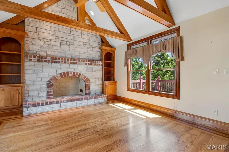 Adjacent to the kitchen, the hearth room features a cozy fireplace and an abundance of natural light, creating a bright and welcoming space for relaxing, entertaining, or enjoying peaceful wooded views. — 4030 Austin Drive, St Charles, MO 63304