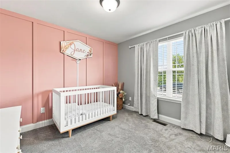 Bedroom one with overhead lighting, window facing front of home, one wall tastefully accented for "baby" girl — 130 Pomodora Circle, Wentzville, MO 63385