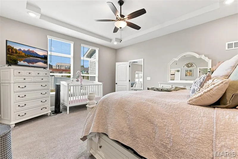 Primary bedroom with tall, coffered ceilings, windows with views of fenced back yard — 130 Pomodora Circle, Wentzville, MO 63385