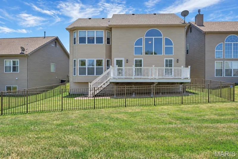 Rear exterior featuring a large deck with white railings, walk-out basement access, and an arched window — 3105 Wheeling Drive, St Charles, MO 63301