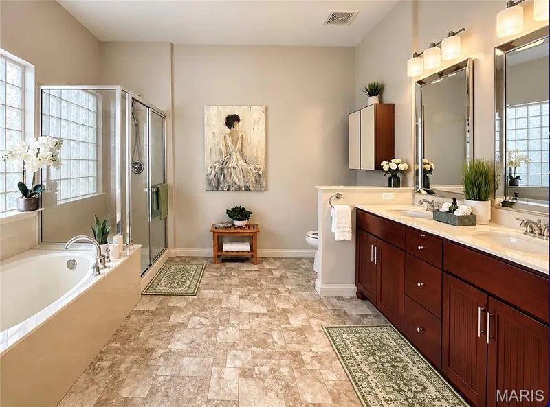Dual vanity with dark wood-finish cabinetry, built-in soaking tub, glass-enclosed shower, and block glass window — 3105 Wheeling Drive, St Charles, MO 63301