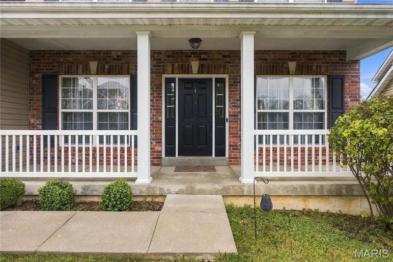 Brick facade with dual windows with shutters, and a dark paneled entry door — 308 Graywynd Court, Lake St. Louis, MO 63367