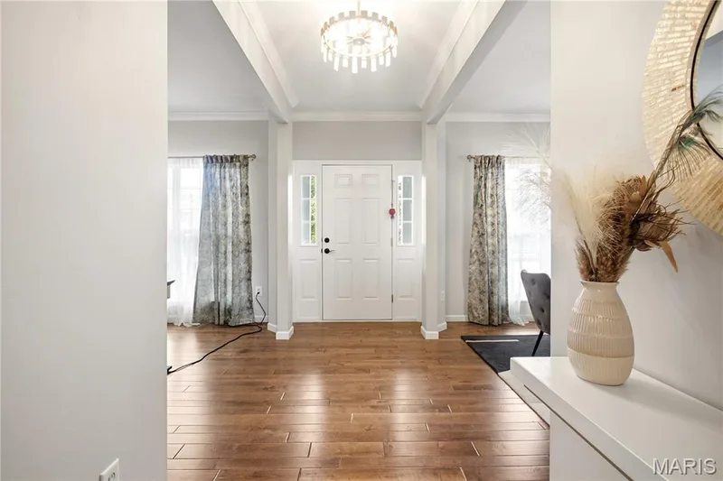 Entryway featuring wood-finish flooring, a white front door with sidelights, and a decorative overhead light fixture — 308 Graywynd Court, Lake St. Louis, MO 63367