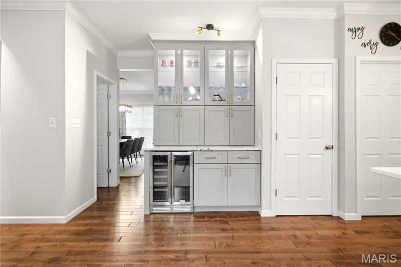 Built-in cabinetry with glass-front uppers, under-cabinet lighting, dual beverage refrigerators, and wood-finish flooring — 308 Graywynd Court, Lake St. Louis, MO 63367