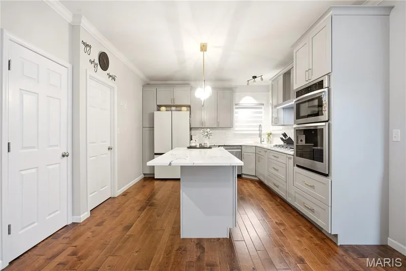 Kitchen featuring wood-finish flooring, light gray cabinetry, stainless steel appliances, a center island with a white countertop, and recessed lighting — 308 Graywynd Court, Lake St. Louis, MO 63367