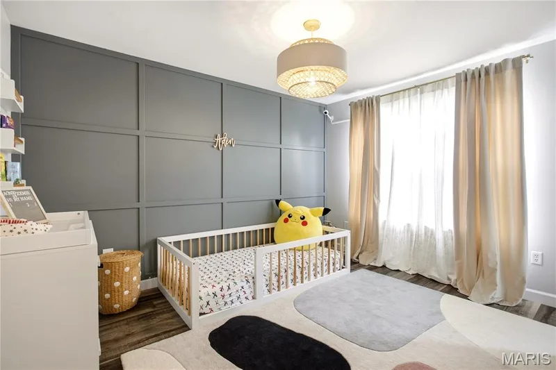 Third Bedroom. Accent wall with paneling, drum chandelier, wood-finish flooring, and window with drapes — 308 Graywynd Court, Lake St. Louis, MO 63367