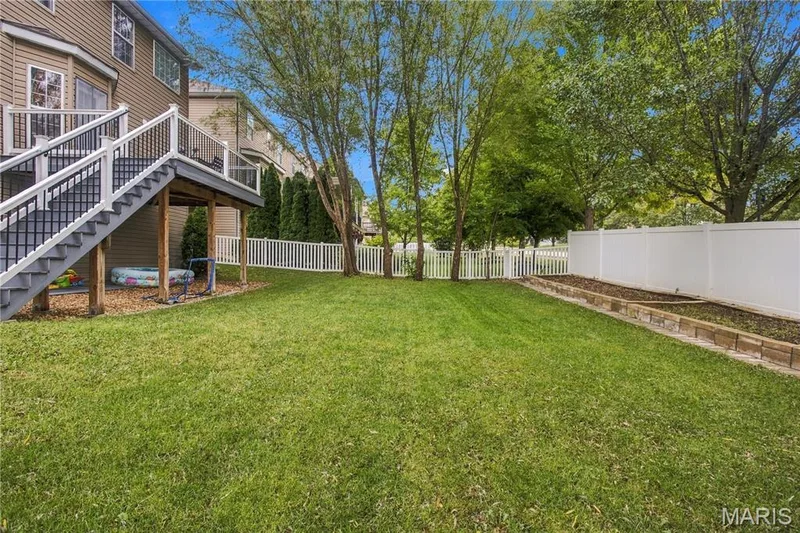 Expansive grassy lawn with a white privacy fence and a white picket fence — 308 Graywynd Court, Lake St. Louis, MO 63367