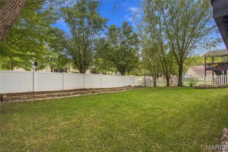 Expansive backyard with a manicured lawn, a white privacy fence. — 308 Graywynd Court, Lake St. Louis, MO 63367