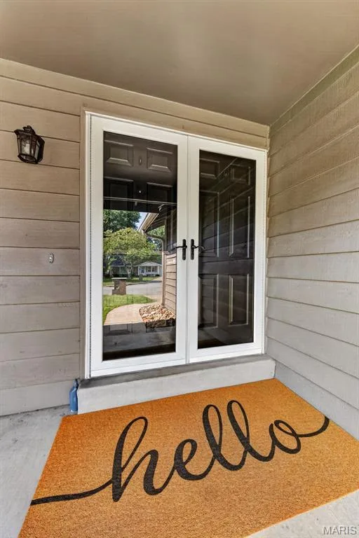 Double storm doors with white framing, exterior light fixture, and horizontal siding — 19 Novella Drive, St Peters, MO 63376