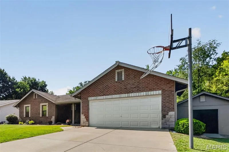 Brick exterior with stone accents, two-car garage, concrete driveway, and established landscaping — 19 Novella Drive, St Peters, MO 63376