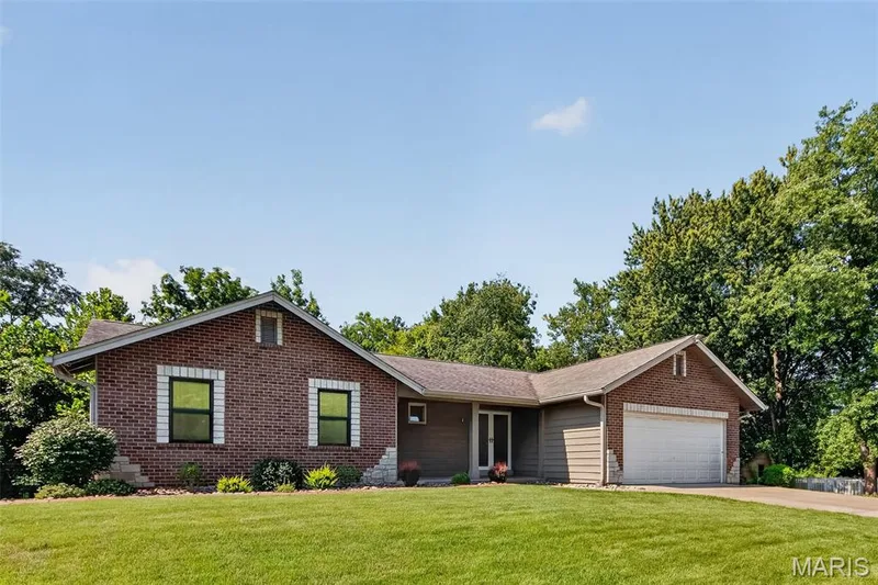 Brick exterior with white trim accents, attached two-car garage, and a lush green lawn — 19 Novella Drive, St Peters, MO 63376