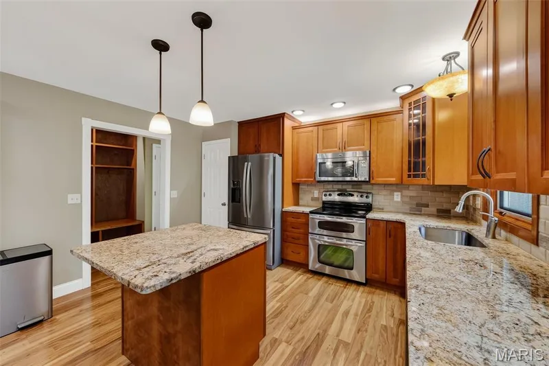 Kitchen with wood-finish flooring, stainless steel appliances, light-toned countertops, wood cabinetry, and recessed lighting — 19 Novella Drive, St Peters, MO 63376