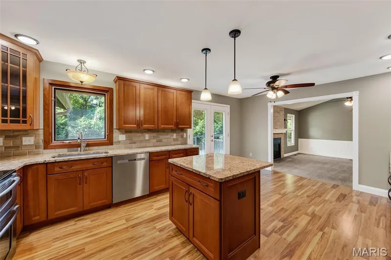 Kitchen featuring wood-finish flooring, wood cabinetry, granite countertops, and stainless steel appliances — 19 Novella Drive, St Peters, MO 63376