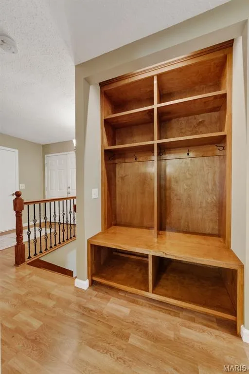 Built-in wood-finish shelving unit featuring integrated hooks and lower compartments — 19 Novella Drive, St Peters, MO 63376