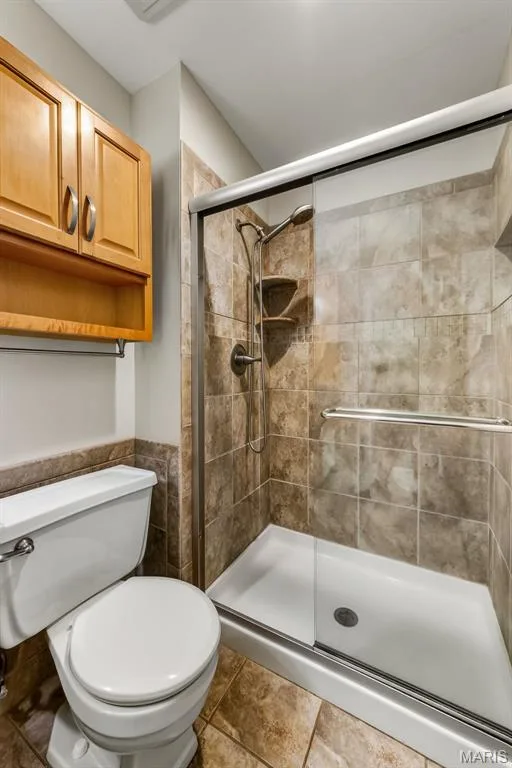 Tiled shower with sliding glass door, white shower pan, and built-in shelving — 19 Novella Drive, St Peters, MO 63376
