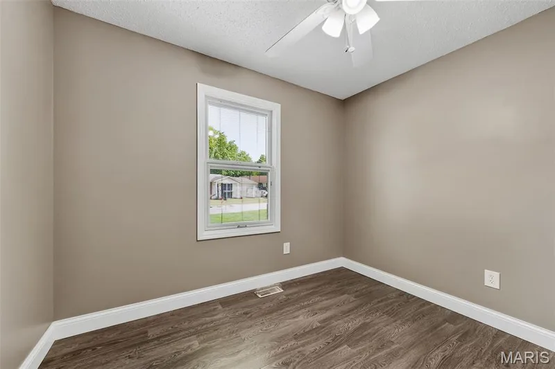 Warm neutral wall tones, wood-finish flooring, white trim, white window frame, and a ceiling fan — 19 Novella Drive, St Peters, MO 63376