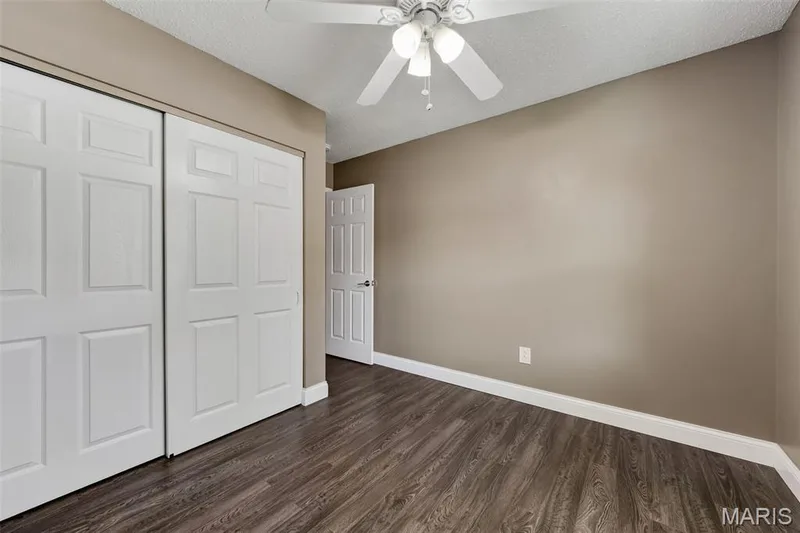 Wood-finish flooring, white trim, sliding panel doors, and a ceiling fan with integrated lighting — 19 Novella Drive, St Peters, MO 63376