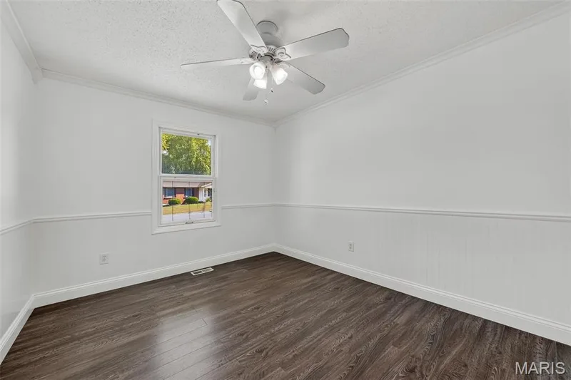 Wood-finish flooring, white paneled wainscoting, white window trim, and a ceiling fan with integrated lighting — 19 Novella Drive, St Peters, MO 63376