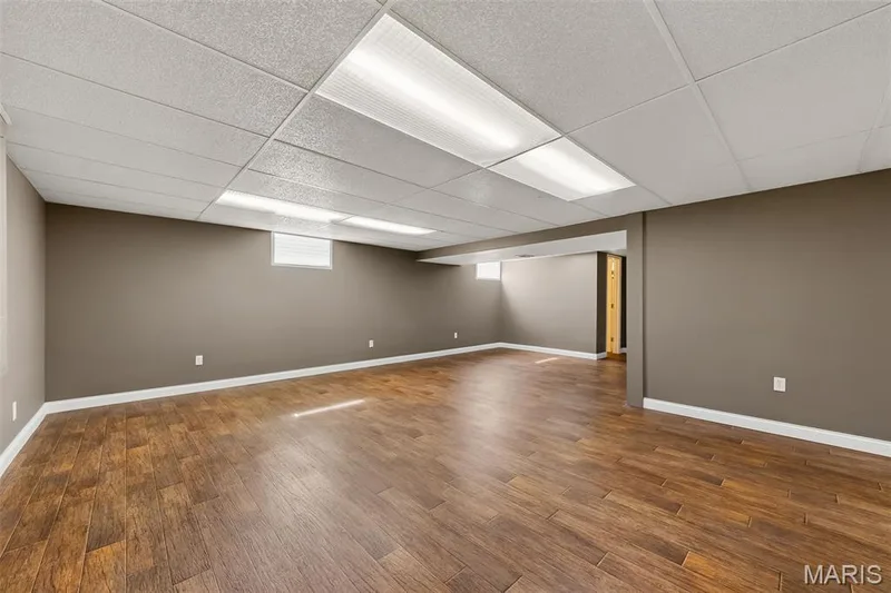 Expansive room featuring wood-finish flooring, neutral wall tones, recessed lighting, and a drop ceiling — 19 Novella Drive, St Peters, MO 63376