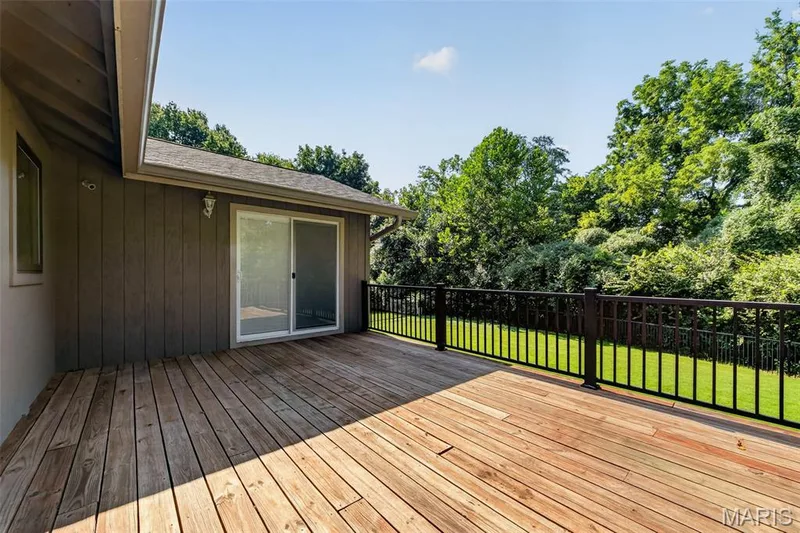 Expansive wood-plank deck with black metal railings and a sliding glass door — 19 Novella Drive, St Peters, MO 63376