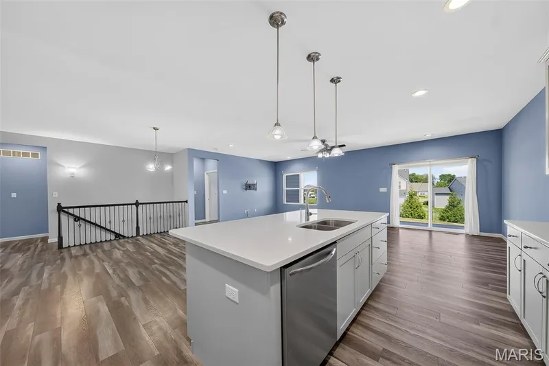 Kitchen island with a solid surface countertop, stainless steel sink, and pendant lighting — 622 Cruden Bay Court, Dardenne Prairie, MO 63368