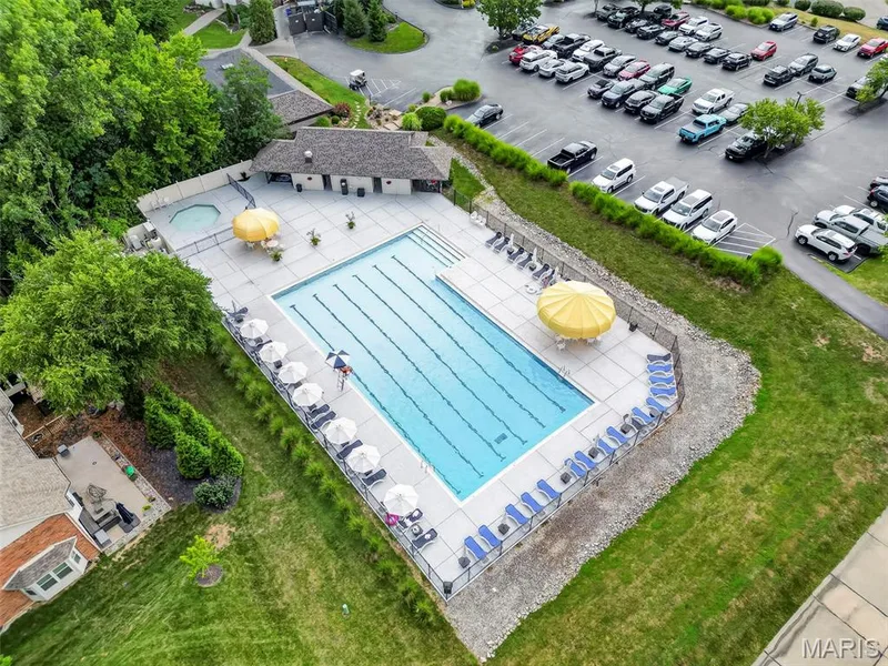 Community swimming pool with lap lanes, adjacent hot tub, and surrounding paved patio — 622 Cruden Bay Court, Dardenne Prairie, MO 63368