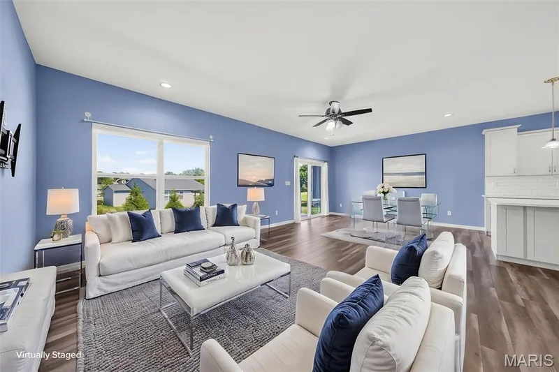 Open-concept living area with wood-finish flooring, white cabinetry, subway tile backsplash, and a ceiling fan with light — 622 Cruden Bay Court, Dardenne Prairie, MO 63368