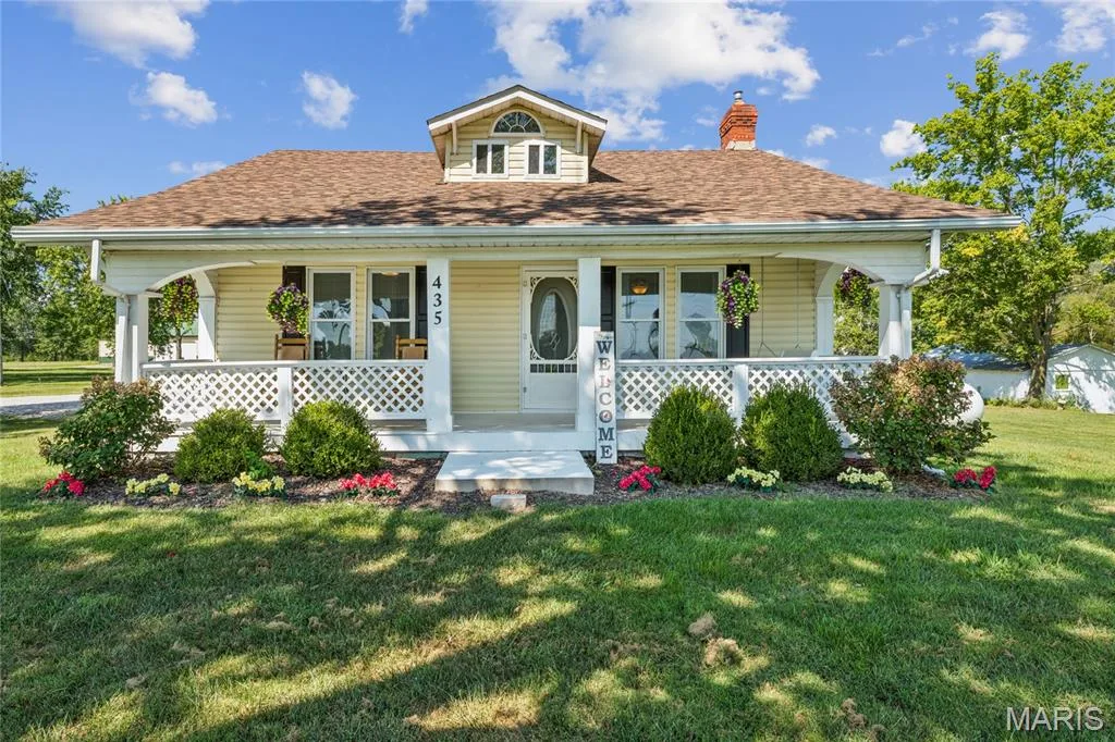 Dormer window, covered front porch, lattice railing, mature landscaping, and brick chimney — 435 Highway T, Foristell, MO 63348