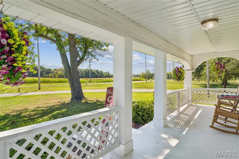 Covered front porch with white lattice railing and columns — 435 Highway T, Foristell, MO 63348