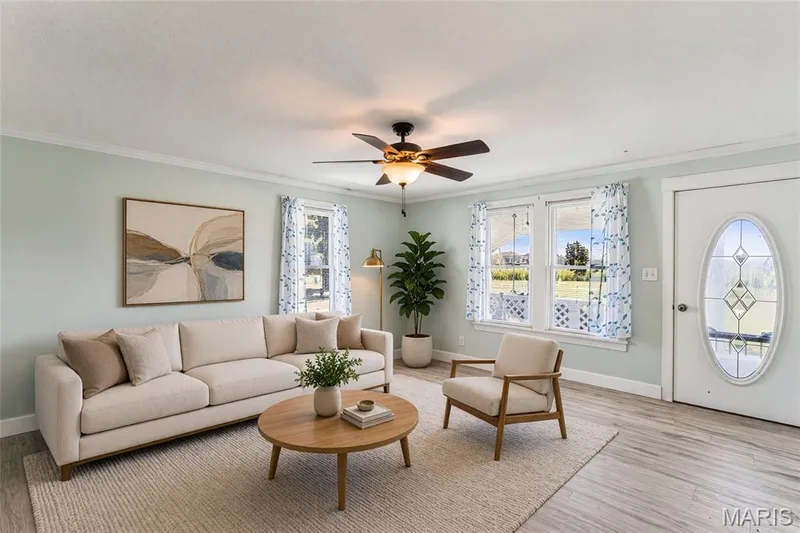 Living space featuring wood-finish flooring, a ceiling fan with integrated lighting, and multiple windows — 435 Highway T, Foristell, MO 63348