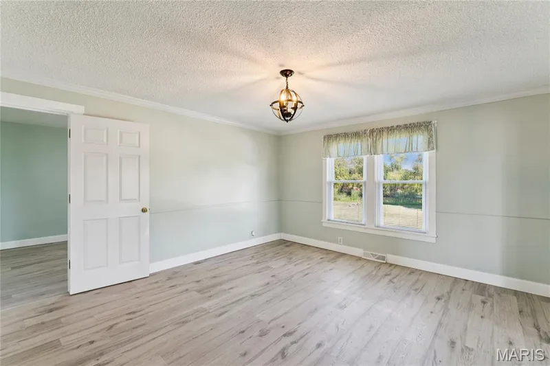 Wood-finish flooring, crown molding, and a decorative ceiling light fixture — 435 Highway T, Foristell, MO 63348