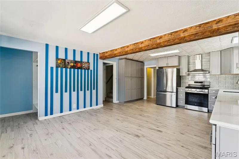 Wood-finish flooring throughout, with a kitchen featuring stainless steel appliances, grey cabinetry, and a subway tile backsplash — 435 Highway T, Foristell, MO 63348