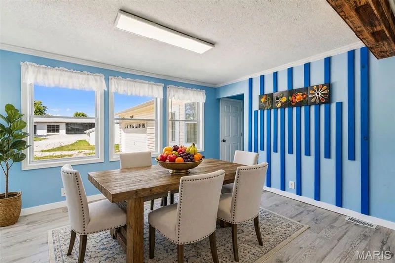 Light wood-finish flooring, three large windows, textured blue accent wall, recessed lighting, white interior door — 435 Highway T, Foristell, MO 63348