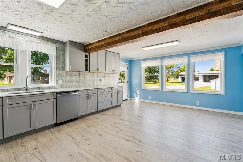 Kitchen featuring gray cabinetry, light wood-finish flooring, a patterned ceiling, and a stainless steel dishwasher — 435 Highway T, Foristell, MO 63348
