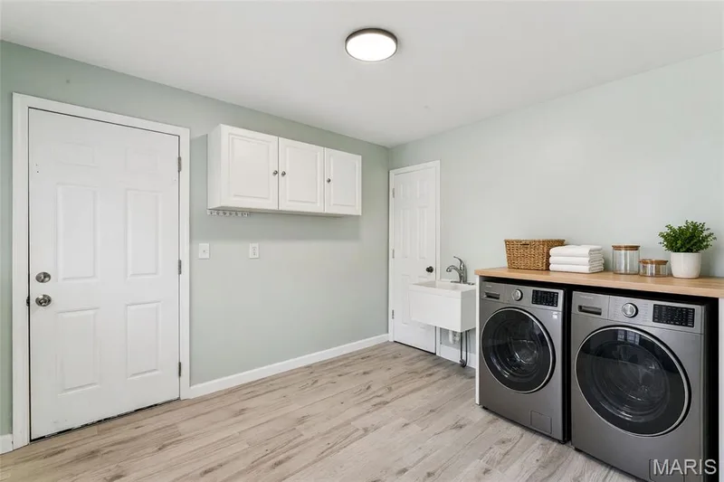 Laundry room featuring wood-finish flooring, white cabinetry, a utility sink, and a countertop surface — 435 Highway T, Foristell, MO 63348