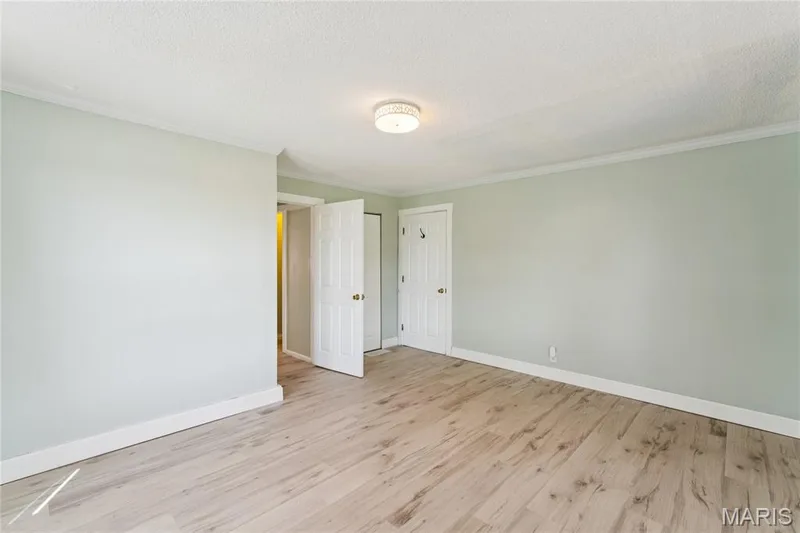 Light wood-finish flooring, crown molding, ceiling-mounted light fixture, and white trim throughout — 435 Highway T, Foristell, MO 63348