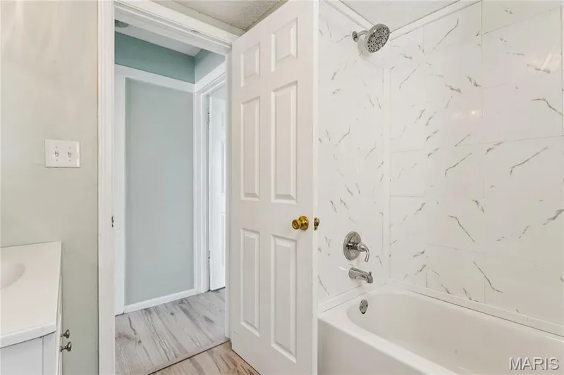 Bathtub with a chrome shower head and faucet, surrounded by white tile with grey veining — 435 Highway T, Foristell, MO 63348