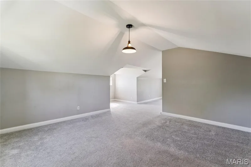 Spacious room with sloped ceilings, gray carpeting, and a modern pendant light fixture — 435 Highway T, Foristell, MO 63348